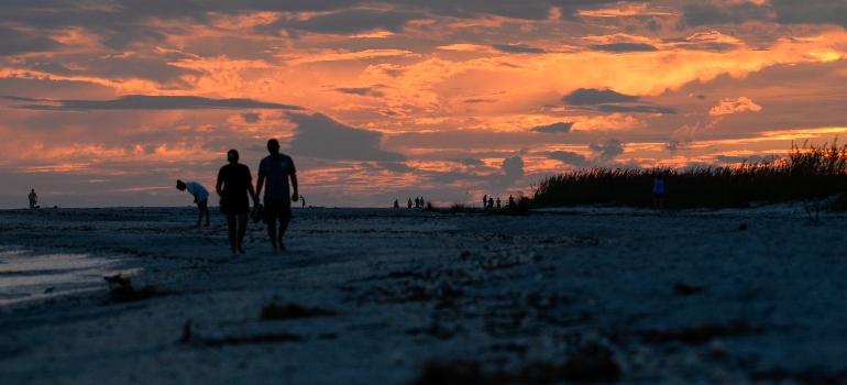 people walking on the beach during the sunset 