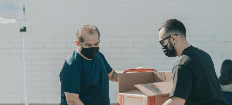 Two men showing you how to maximize space in your storage unit by sorting boxes