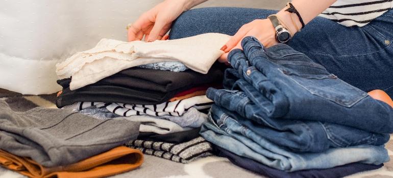 a person sorting clothes and thinking about storage tips for a seamless transition into fall